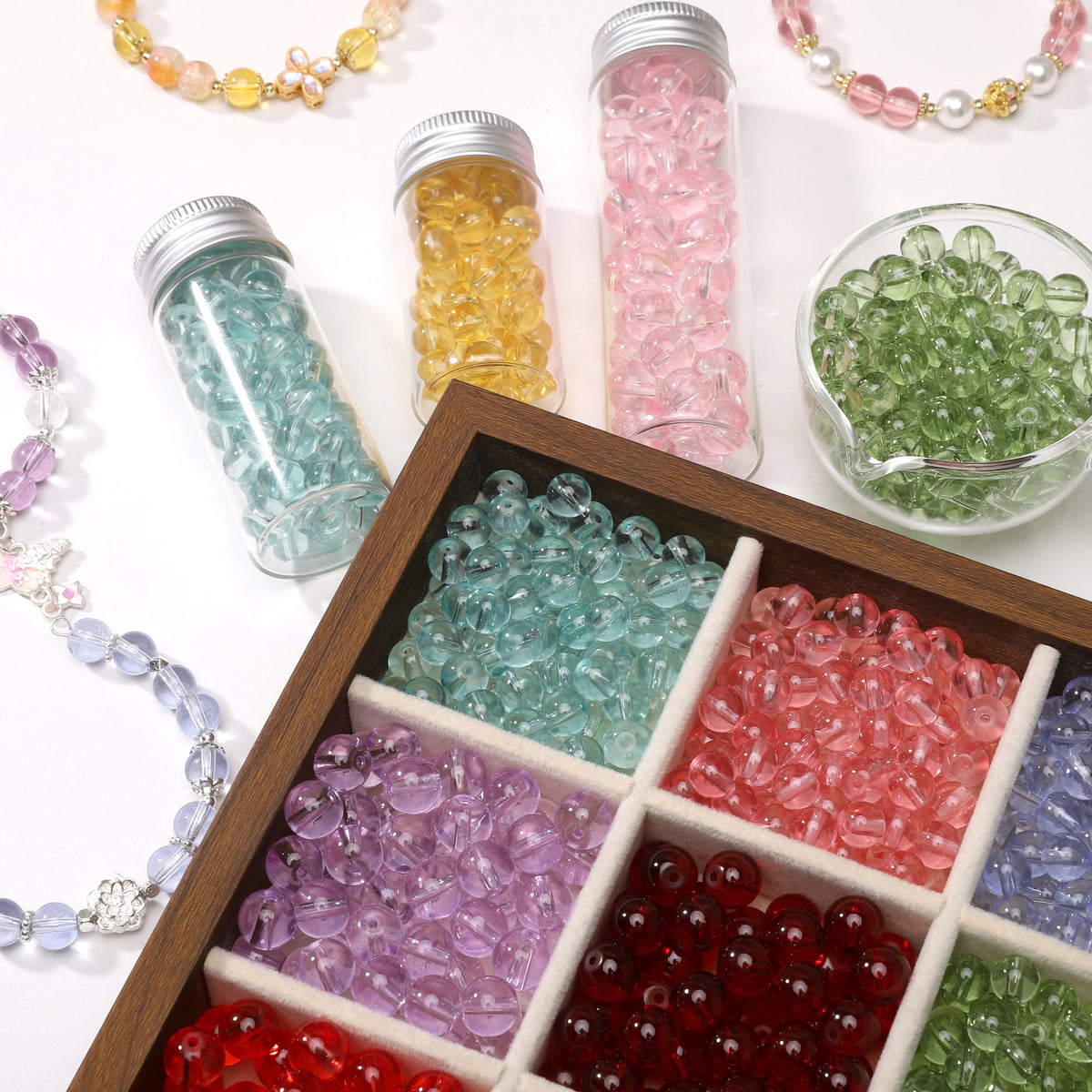 A collection of round glass spacer beads in various colors like pink, green, yellow, and purple are displayed in glass jars a