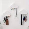 A white magnetic cloud key hanger displaying various keys and pens on a white wall.