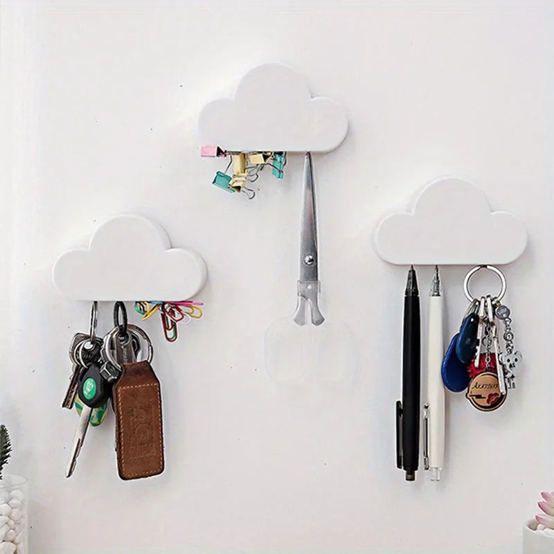 A white magnetic cloud key hanger displaying various keys and pens on a white wall.