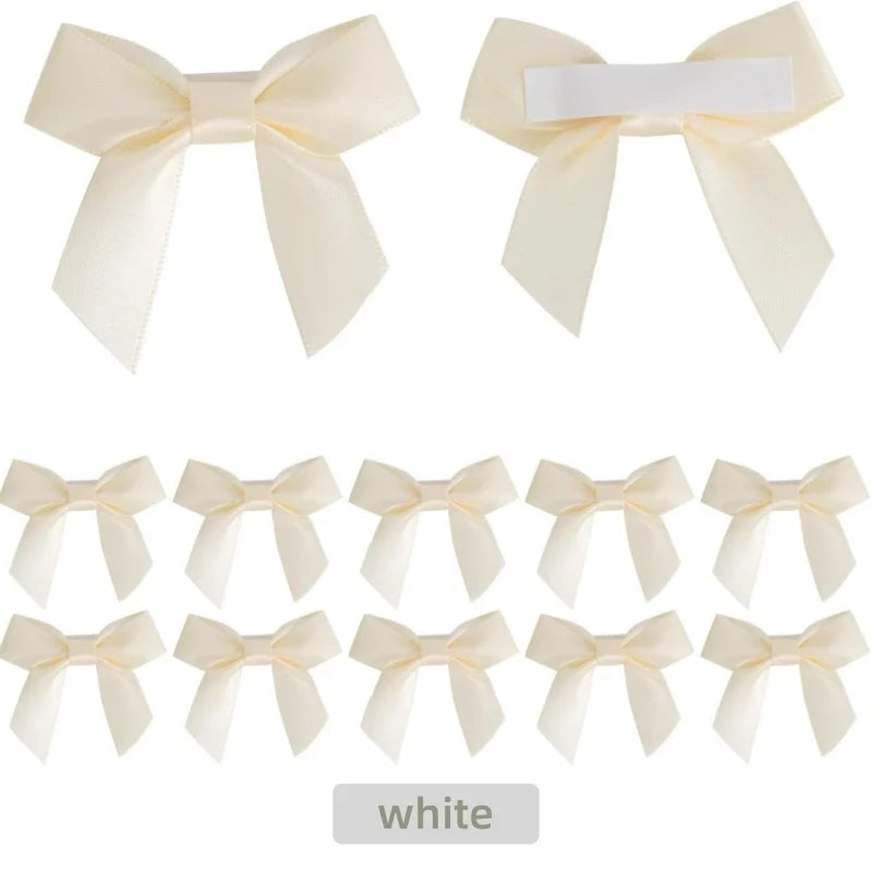 A set of five white satin ribbon bows with self-adhesive backing for crafting and gift wrapping.