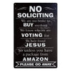 A black metal sign with white text humorously stating no soliciting and voting for Jesus, with a request to go away.