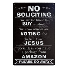 A black metal sign with white text humorously stating no soliciting and voting for Jesus, with a request to go away.