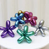 A collection of glossy latex modeling balloons in shades of blue, purple, gold, and silver arranged on a white surface.