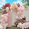 A large arrangement of pastel pink and beige latex balloons forming a decorative backdrop for a celebration.