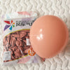 A large, round pastel pink latex balloon is shown next to its packaging.