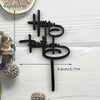 Black acrylic birthday cake topper set with text and a stick on a white wooden background
