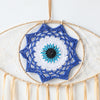 Handmade boho evil eye dream catcher wall decor featuring a blue and white eye design with hanging threads