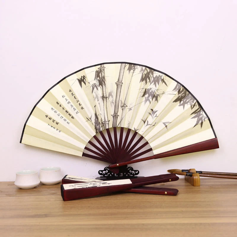 A retro folding silk and bamboo decorative fan with a light cream color and dark wood accents.