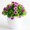 Un arrangement vibrant de fleurs de bonsaï artificielles violettes et roses, dans un vase en céramique blanche.