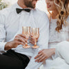 A couple is holding a set of reusable plastic wine glasses during a celebration.