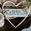 Weißes Harzherz-Anhänger mit der deutschen Phrase "Schön dass Du da bist", auf braunem Stoff.