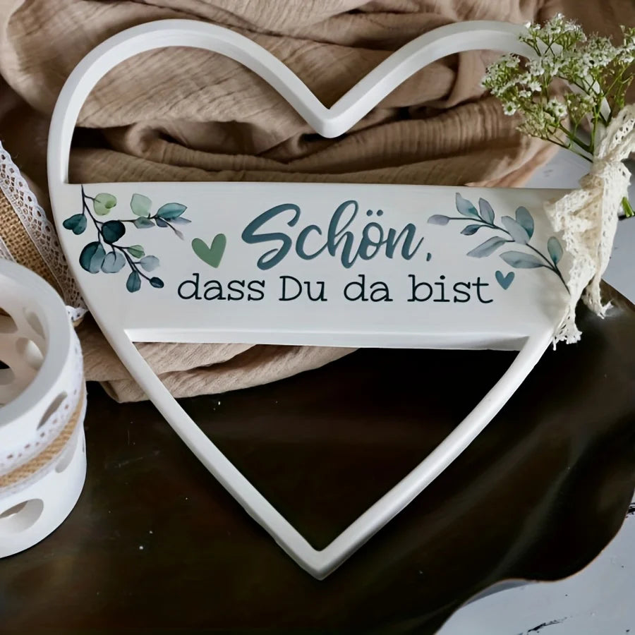 Weißes Harzherz-Anhänger mit der deutschen Phrase "Schön dass Du da bist", auf braunem Stoff.