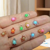 A hand displays various glow-in-the-dark resin turtle figurines in pink, green, and yellow colors.