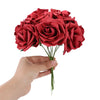 A hand holds a bouquet of twenty deep red lifelike foam rose stems for weddings and home decor.
