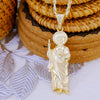 A gold-plated pendant necklace featuring a figure of Saint Jude, set against a background of woven baskets and natural wood.