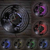 A collection of five vintage vinyl record wall clocks with black and purple designs mounted on a brick wall.