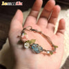 A hand holds a raw aquamarine macrame bracelet featuring rose and green floral accents.