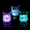 A glass cup filled with glowing blue and purple LED lights reflecting on a dark surface.