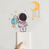 A set of luminous astronaut, star, and moon wall stickers on a white background.