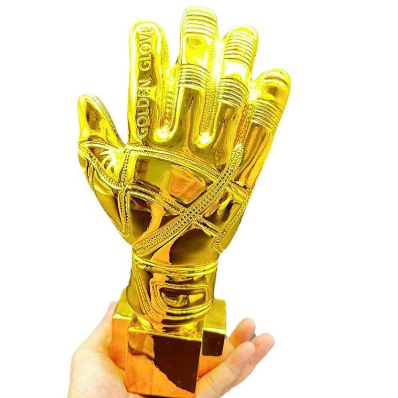 A golden glove award trophy shaped like a hand, held in a person's hand.