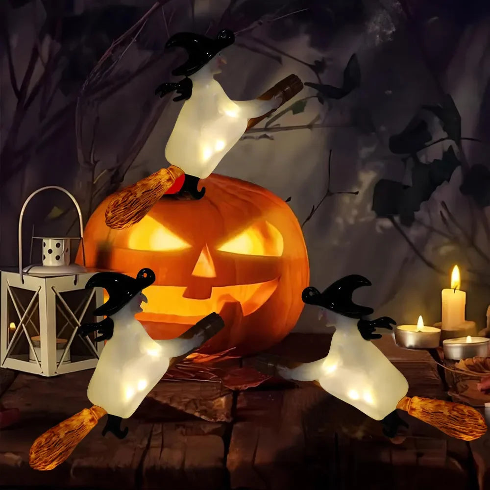 A carved pumpkin jack-o'-lantern is surrounded by twelve glowing white LED candles shaped like bats and a magic wand.