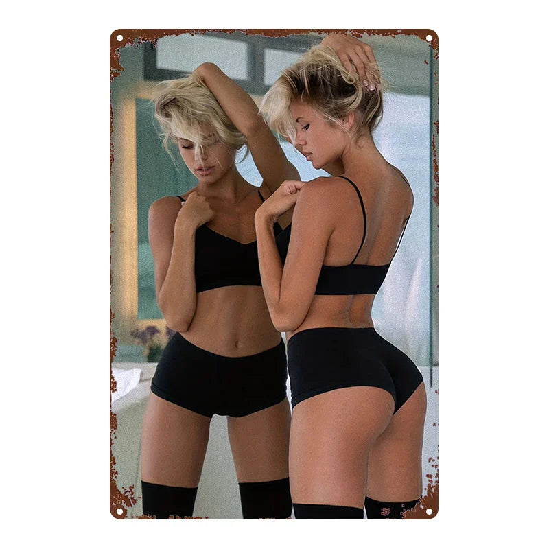 A woman with blonde hair wearing a black sports bra and shorts posing for a photo in a mirror.