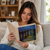 A woman is reading a 6-inch laminated photo album featuring a nighttime landscape with illuminated trees.
