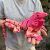 A hand holds a pink, articulated 3D printed lizard figurine for home decor.