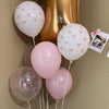 A cluster of pastel pink and white balloons tied with pink bows against a neutral background.