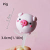 A pink pig cake topper is shown against a light pink background, measured by a ruler.