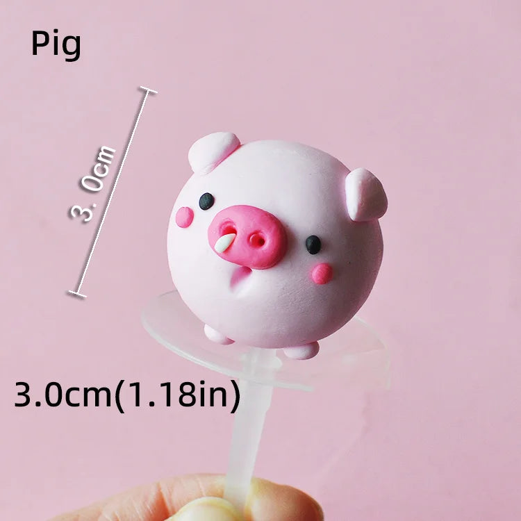 A pink pig cake topper is shown against a light pink background, measured by a ruler.