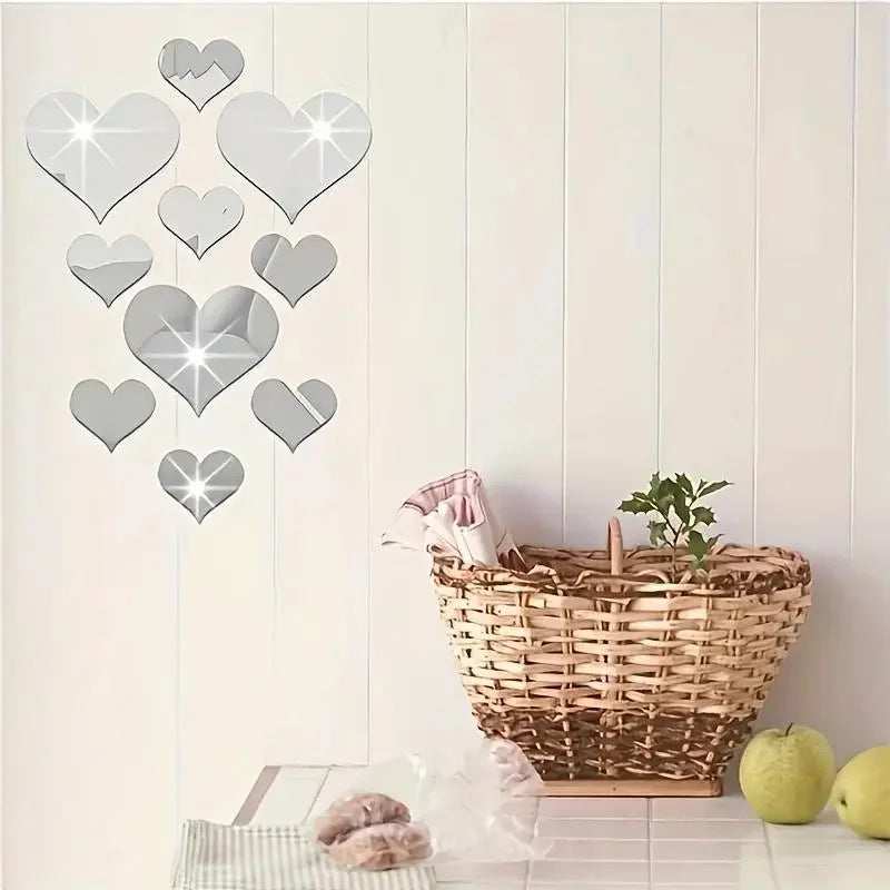 A set of silver 3D love heart mirror wall stickers displayed next to a woven basket and green plant.