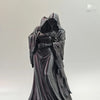 A dark, flowing hooded figure collectible figurine in a draped gown.
