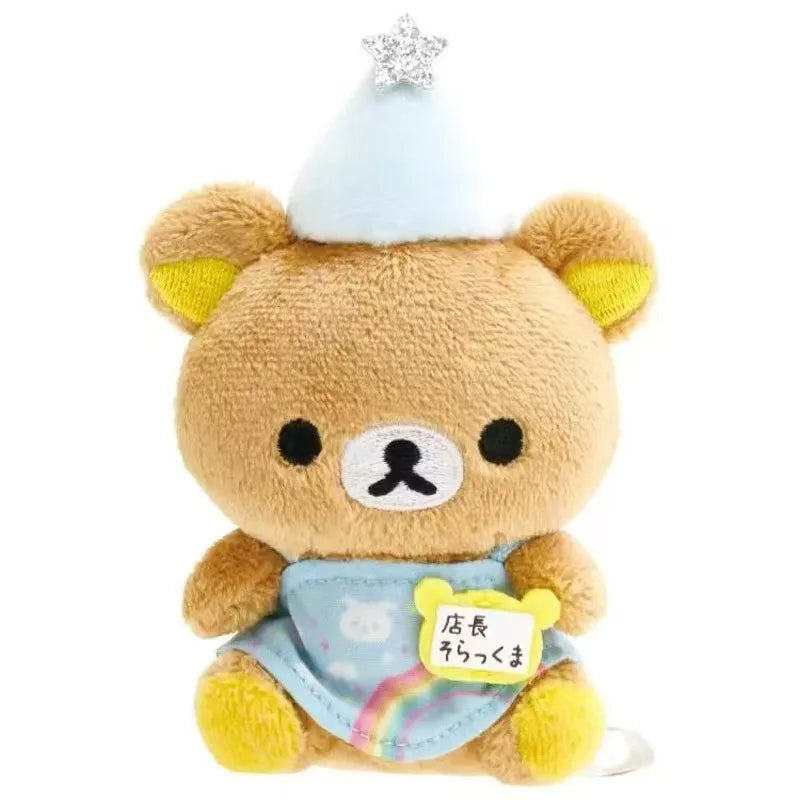 A cute brown Rilakkuma bear plush toy with a white hat and a blue bag pendant.