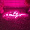 A neon sign spelling out The Midnight is displayed on a textured pink wall.