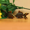 A pair of retro brass goldfish statues resting on a smooth surface with green foliage in the background.