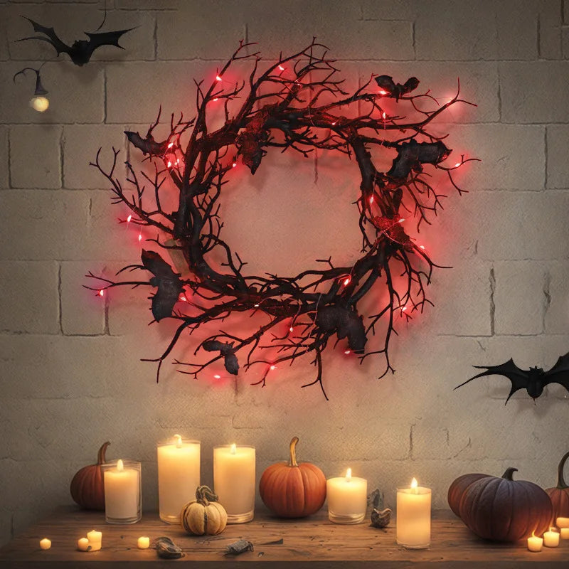 A dark branch bat wreath made of artificial black branches and pink lights hangs on a white brick wall.