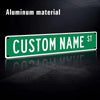 A green aluminum street sign with custom name text on a dark background.