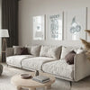 A modern living room features a light sofa, wooden coffee table, and framed art prints on the wall.
