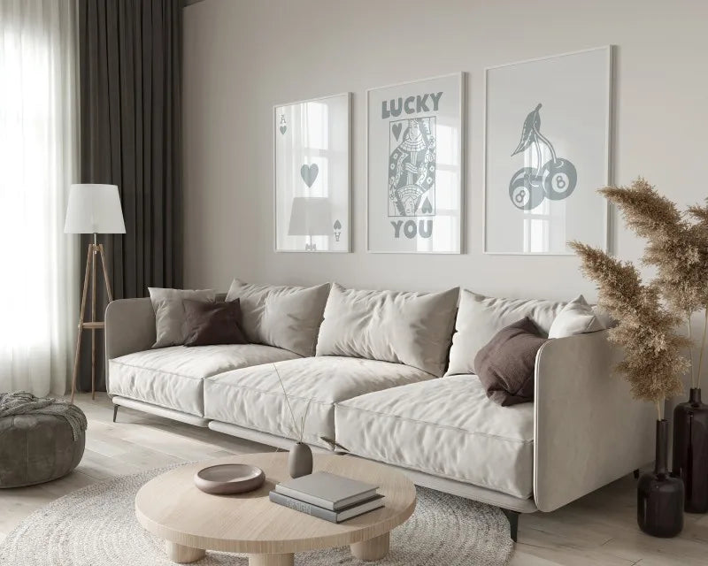 A modern living room features a light sofa, wooden coffee table, and framed art prints on the wall.