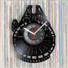 A black wall clock shaped like the Millennium Falcon, featuring a circular face and a vinyl record background.