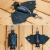 Black leather bat wallet keychain with zipper coin purse resting on a wooden surface.