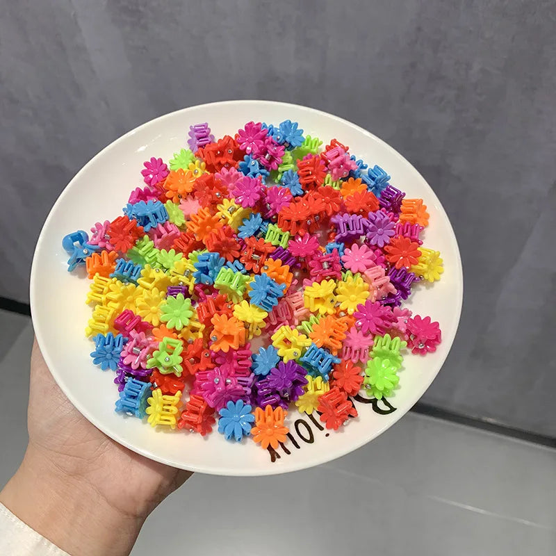 A pile of colorful flower and star hair claw clips for kids in various bright colors.