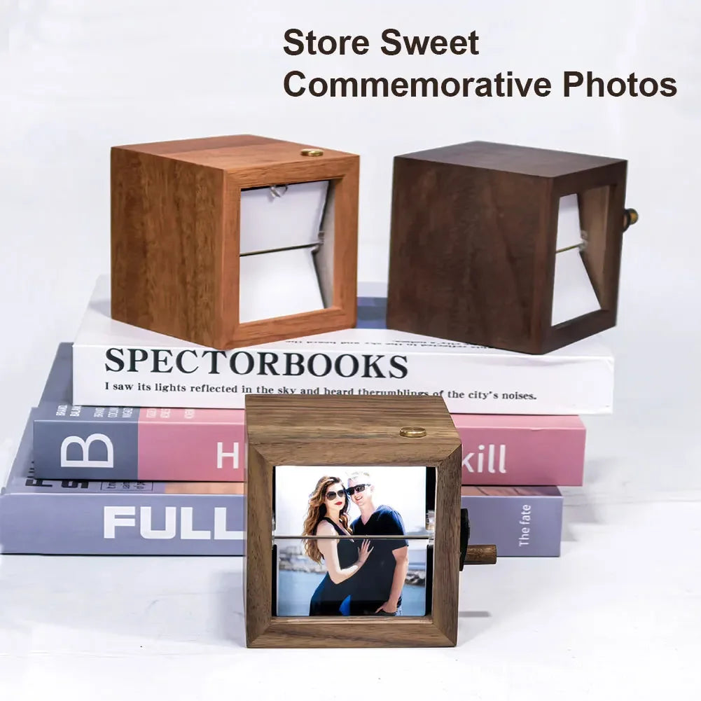 A wooden hand-crank flip photo frame with an LED light displayed on a stack of books.
