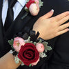 A hand holds a bouquet of artificial roses featuring pink and deep red blooms with dark foliage.