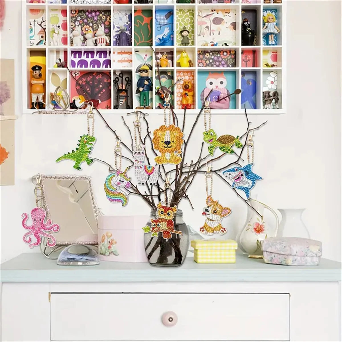A display of colorful DIY diamond painting keychains hanging from a branch against a white background.