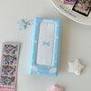 A light blue photo booth album with a clear window featuring a bow and stars, next to a star charm.