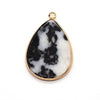 A teardrop-shaped pendant charm made of black and white marble set in a gold-colored bezel.