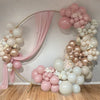 A large arch made of pink and white balloons decorated with floral accents for a celebration