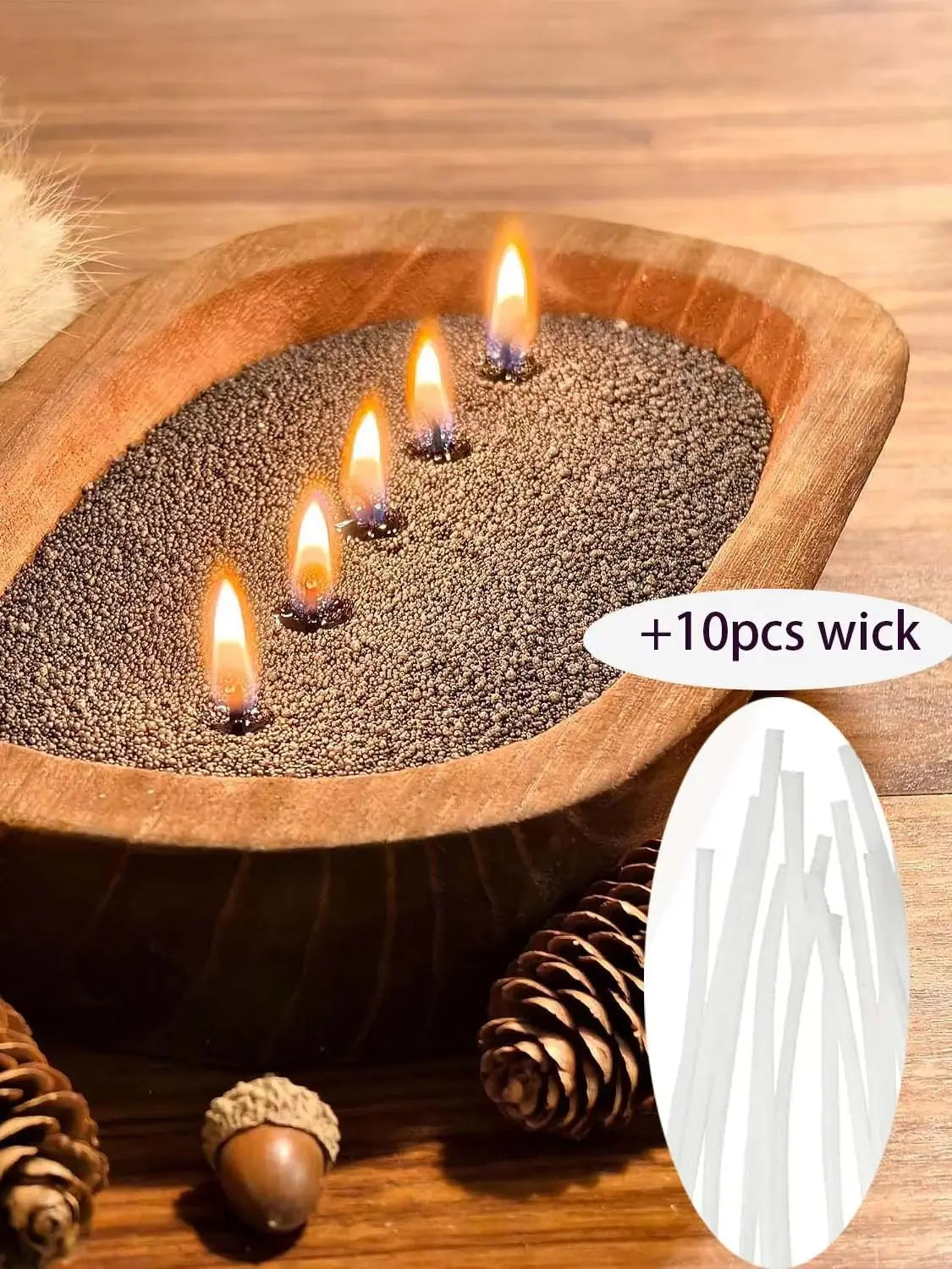A wooden bowl filled with dark, pearled material and several lit candles on a wooden surface.